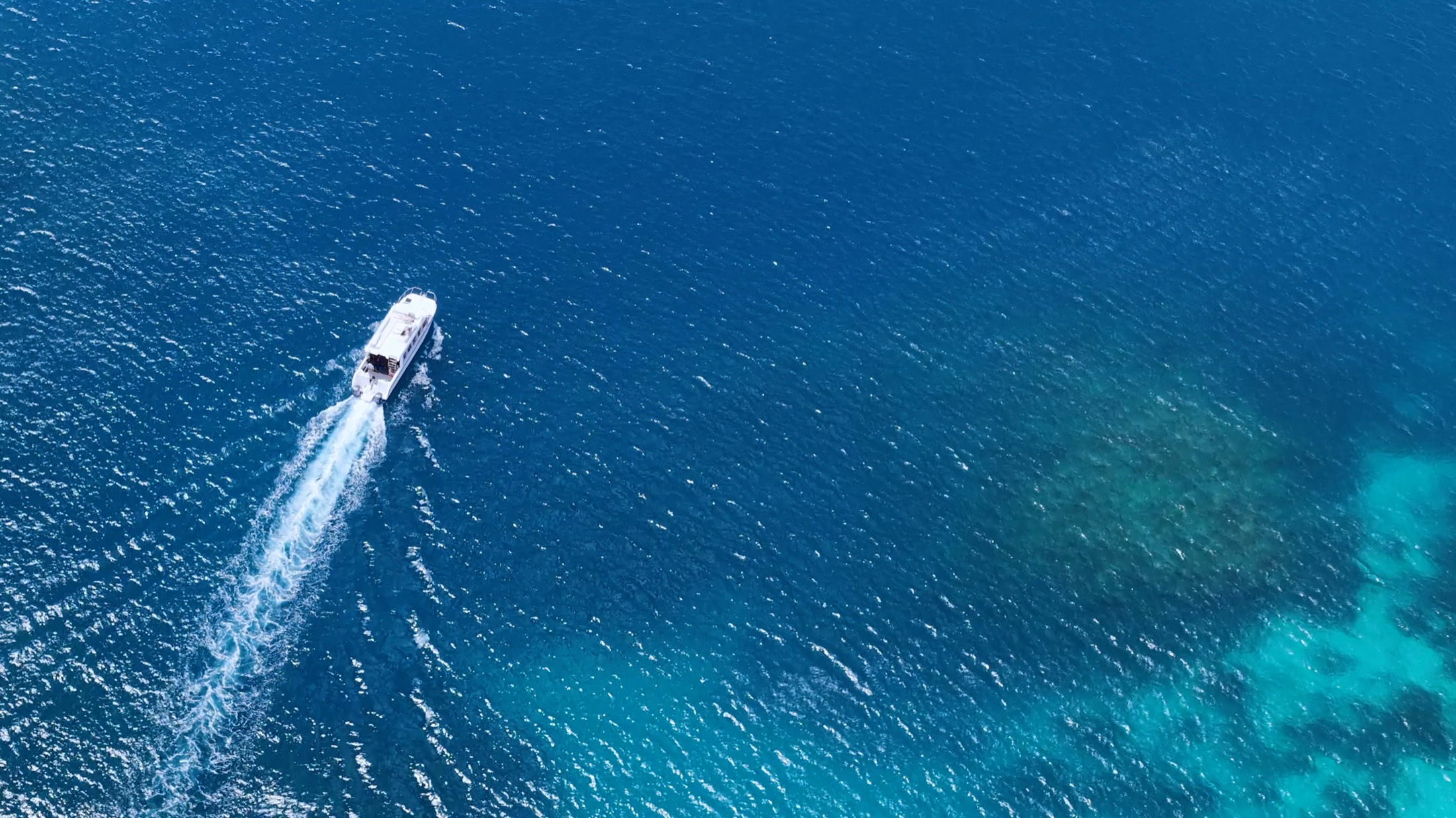 White motor yacht speeding across turquoise tropical water